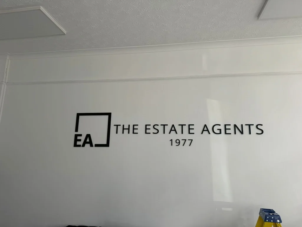 Black dimensional Estate Agents lettering mounted directly to a white interior wall