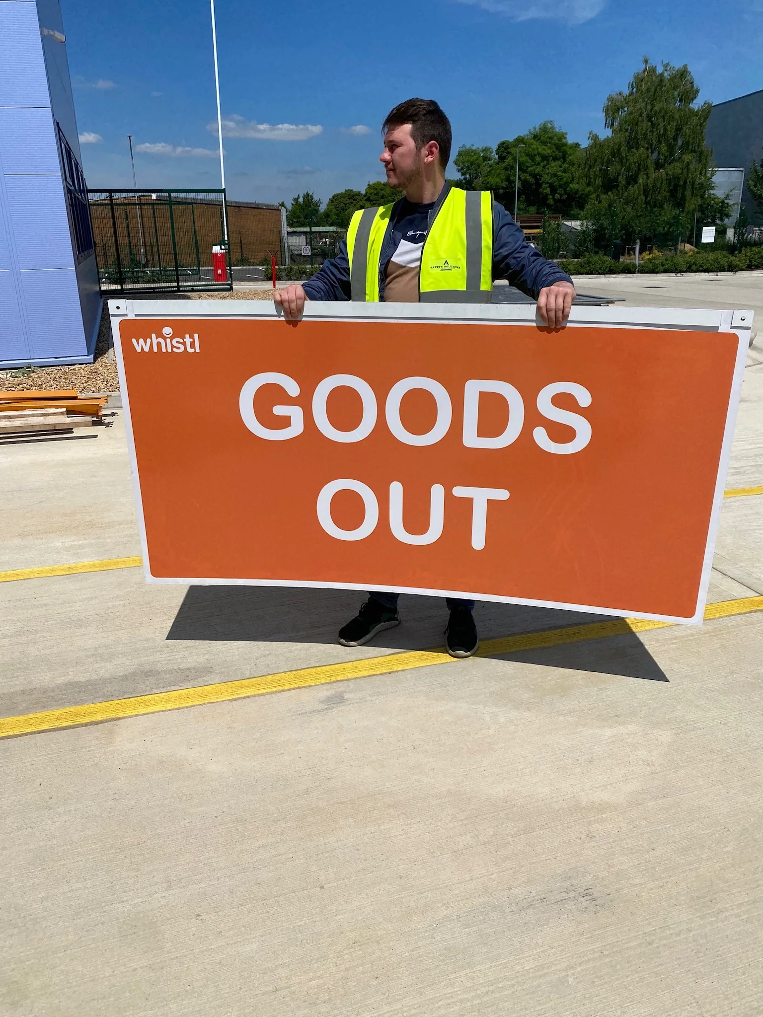 Installer holding a large orange Whistl goods out sign panel
